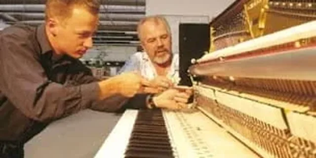 Técnicos trabajando en un piano vertical