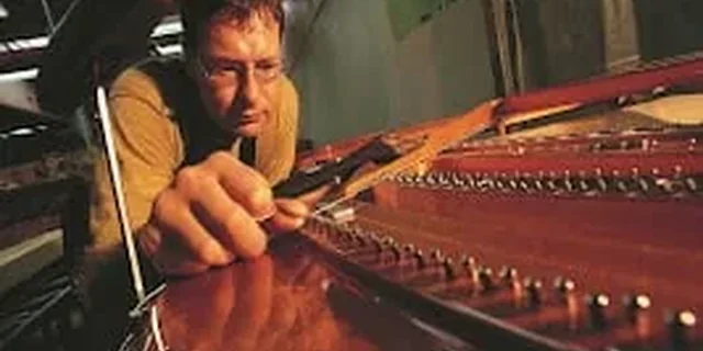 Técnico trabajando en un piano de cola